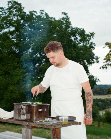 Kruh Dining kuchař v bílém griluje zeleninu na yakitori grilu v domě Oskar.